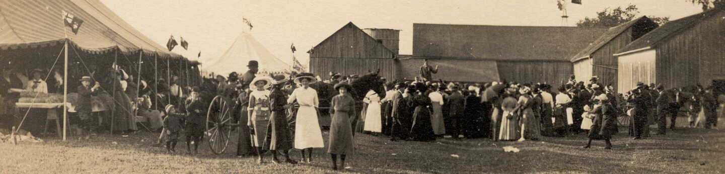 Photograph of people in crowd around fair or circus tent